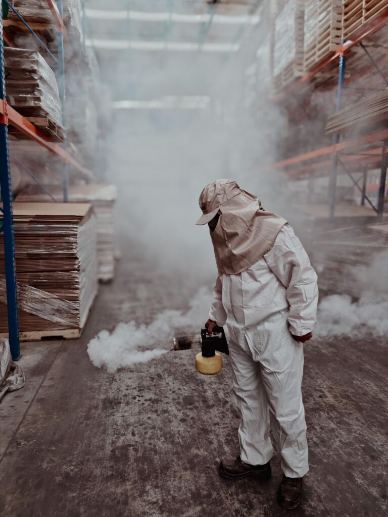 Pest control technician in protective gear carrying out fumigation