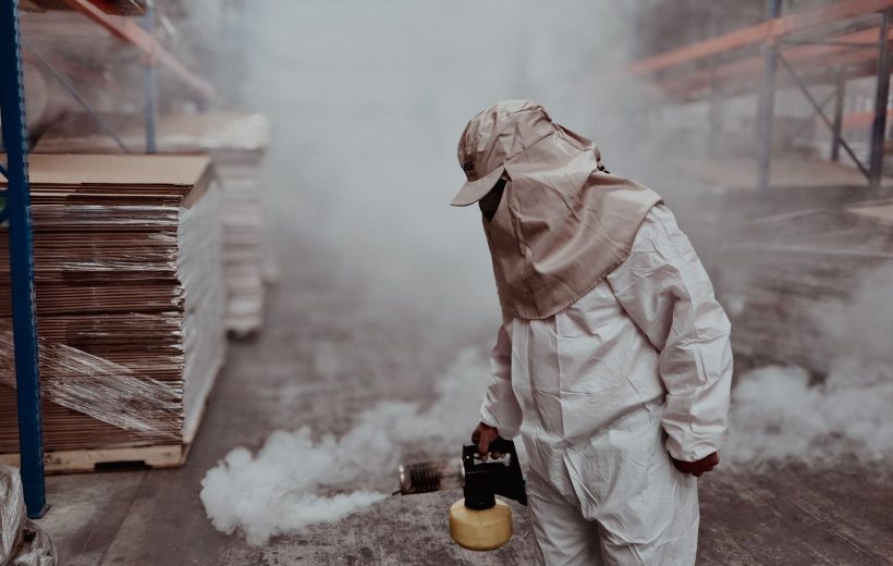 Pest control technician in protective gear carrying out fumigation