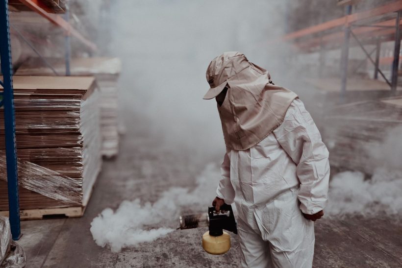 Pest control technician in protective gear carrying out fumigation