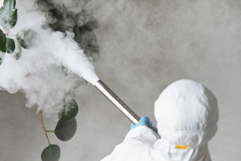 Technician in protective clothing applying indoor fumigation treatment